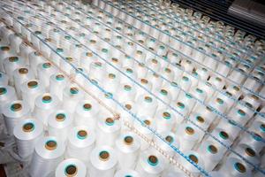Top view of A lot of white yarn spools in a textile factory. White yarn spools in a clothing factory. photo