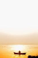 Evening golden sunset time, a fisherman fishing on the seaside on a boat. photo