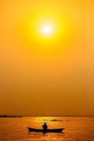 Evening golden sunset time, a fisherman fishing on the seaside on a boat. photo