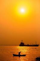 noche dorado puesta de sol tiempo, un pescador pescar en el playa en un bote. foto