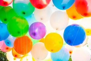 Sunlight against colorful gas-filled balloons attached to the yarn. Colorful balloons background. photo