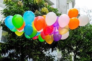 Colorful balloons filled with gas tied to the thread are flying. photo