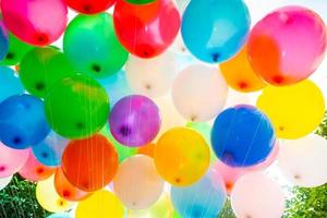 Sunlight against colorful gas-filled balloons attached to the yarn. Colorful balloons background. photo