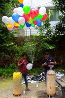 Bangladesh septiembre 08, 2020 dos globo vendedores son inyectando gas dentro algunos vistoso globos mediante dos gas cilindros a dhaka, bangladesh foto