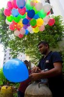 Bangladesh septiembre 08, 2020 dos globo vendedores son inyectando gas dentro algunos vistoso globos mediante dos gas cilindros a dhaka, bangladesh foto