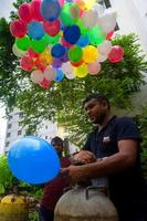 Bangladesh septiembre 08, 2020 dos globo vendedores son inyectando gas dentro algunos vistoso globos mediante dos gas cilindros a dhaka, bangladesh foto