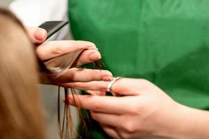 Closeup of a hairdresser cutting hair tips of a female customer in a beauty salon. photo