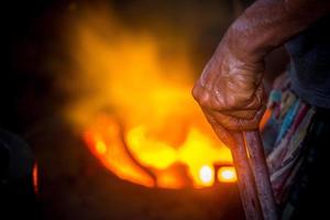 inseguro trabajador manos. un local acero máquina partes haciendo yarda trabajador derritiendo chatarra en caliente horno. foto