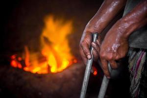 Unsafe worker hands. A local steel machine parts making yard worker melting scrap on hot furnace. photo