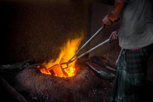 Unsafe worker hands. A local steel machine parts making yard worker melting scrap on hot furnace. photo