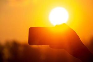 tomando imágenes con un móvil cámara a amanecer. selfie escoge arriba con un móvil cámara en el dorado ligero de amanecer. foto