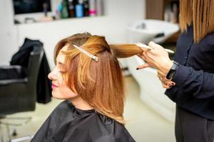 el hembra cliente recepción un Corte de pelo a el belleza salón, joven mujer disfrutando consiguiendo un nuevo peinado. foto