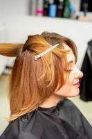 The female client receiving a haircut at the beauty salon, young woman enjoying getting a new hairstyle. photo