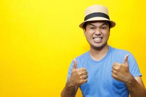 Portrait of Hipster young man young happy man casual dress blue striped t-shirt and wear a hats. Gesture emotion extend the arms shy modest on studio portraits set color yellow background. photo