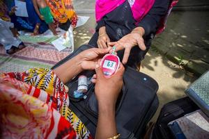 mujer comprobación azúcar nivel con glucómetro utilizando un sangre muestra a narsingdi, bangladesh aprender a utilizar un glucómetro concepto de diabetes tratamiento. foto