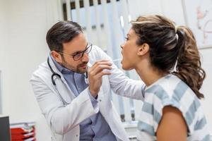 médico utilizando inspección espátula a examinar paciente garganta. ent médico haciendo garganta examen de un mujer. paciente abrió su boca a garganta chequeo foto