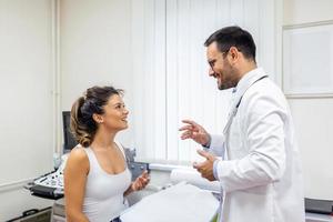 masculino médico consultante hembra paciente a consulta. profesional médico vistiendo blanco Saco hablando a mujer a cita visitar en clínica. foto