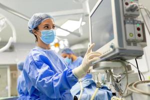 Concentrated Surgical team operating a patient in an operation theater. Well-trained anesthesiologist with years of training with complex machines follows the patient throughout the surgery. photo
