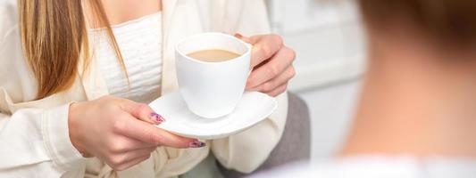 Young caucasian unrecognizable woman holding a cup of hot drink at a doctor's appointment in hospital office. photo