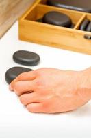 Hand of masseur takes black massage stones from the table in spa salon. photo