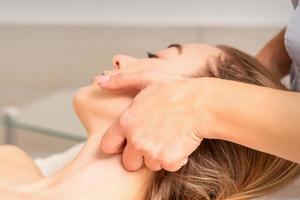 cosmetólogo haciendo linfático drenaje cara masaje o Levantamiento facial masaje a el belleza salón. foto