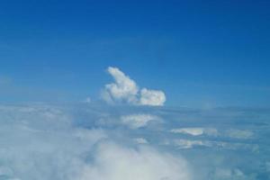 white clouds against the blue sky seen from the flight from the windows of the plane photo