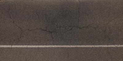 top view of surface of asphalt road made of small stones and sand with cracks photo