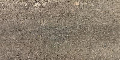 top view of surface of asphalt road made of small stones and sand with cracks photo