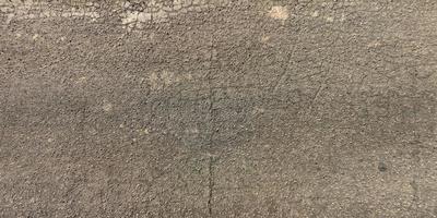 top view of surface of asphalt road made of small stones and sand with cracks photo