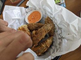 Potato wedges with cheese sauce over the white papers. The photo is suitable to use for food background, poster and food content media.