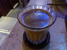 Close up photo of milk tea over the wooden table. The photo is suitable to use for coffee shop background, menu poster and coffee content media.