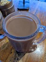 Close up photo of milk tea over the wooden table. The photo is suitable to use for coffee shop background, menu poster and coffee content media.