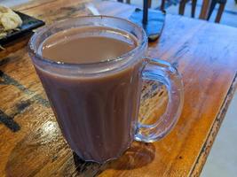 Close up photo of milk tea over the wooden table. The photo is suitable to use for coffee shop background, menu poster and coffee content media.