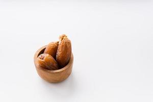 Dried dates fruit in wooden bowl isolated on white background. photo