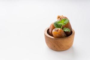 Dried dates fruit in wooden bowl isolated on white background. photo