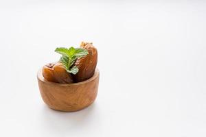 Dried dates fruit in wooden bowl isolated on white background. photo