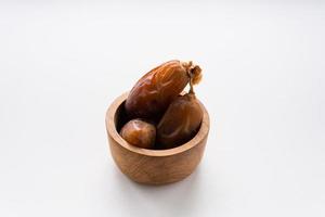 Dried dates fruit in wooden bowl isolated on white background. photo