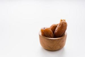 Dried dates fruit in wooden bowl isolated on white background. photo