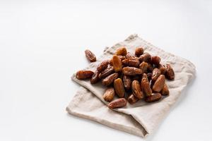 Dried dates fruit in wooden tray with soft napkin isolated on white background. photo