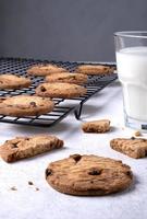 Baked oatmeal cookies with chocolate chips on a metal cooling rack and milk in a glass. photo