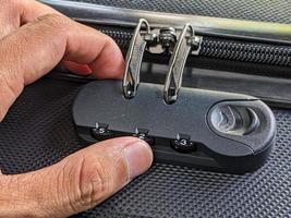 man hands unlocking a code padlock on a suitcase photo