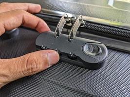 man hands unlocking a code padlock on a suitcase photo