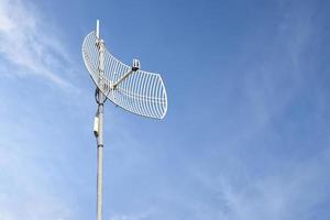 Internet wireless wifi receiver and repeater installed on metal pole on the roof of the building to service internet to users in local village, soft and selective focus. photo