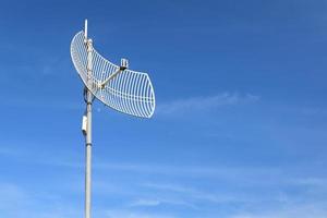 Internet wireless wifi receiver and repeater installed on metal pole on the roof of the building to service internet to users in local village, soft and selective focus. photo