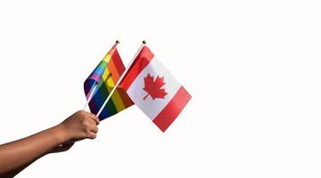 aislado Canadá bandera y arco iris bandera participación en mano recorte caminos', concepto para celebrando de lgbt personas en Canadá en orgullo mes, junio. foto