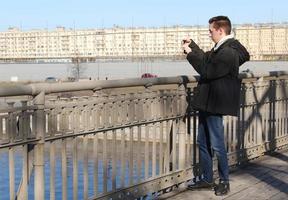 Sankt Petersburgo Rusia - 04 08 2023 hombre fotografiando río mediante inteligente teléfono foto