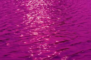 Defocus blurred transparent purple colored clear calm water surface texture with splash, bubble. Shining purple water ripple background. Surface of water in swimming pool. Purple bubble water shine. photo