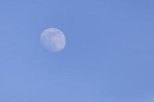 waxing crescent moon in a blue sky photo