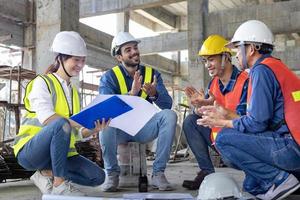 Team of engineer, architect, contractor and foreman meeting and consulting while clapping at the construction building site with floor plan for real estate development project industry and housing photo