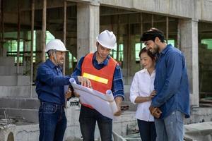 Newly wed couple is meeting with engineering contractor at their under construction house to inspect the building progress and quality control for home ownership and real estate development concept photo